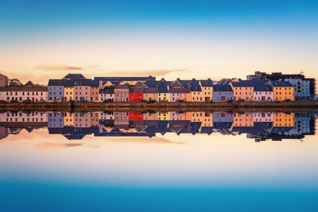 Colorful houses along a calm waterway at sunset, mirrored in the still surface like a perfect reflection.