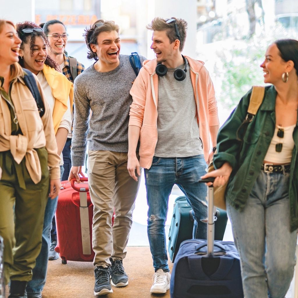 Groupe d'amis souriants arrivant avec leurs valises dans leur lieu de vacances via le programme Départ 18:25 de l'ANCV.