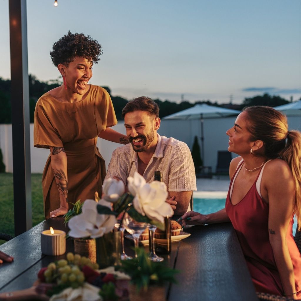 Dîner entre amis sur la terrasse d'une villa avec piscine au coucher du soleil, réservée grâce au programme Départ 18:25 de l'ANCV.