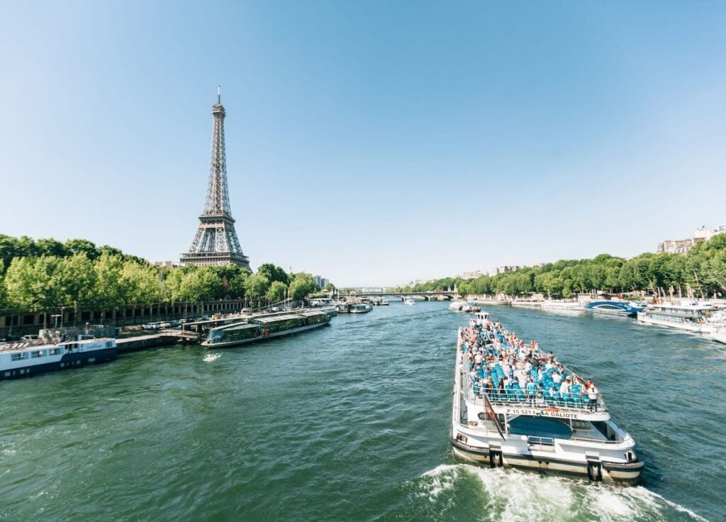 Tour boat cruising on the Seine past the Eiffel Tower on a sunny day in Paris.